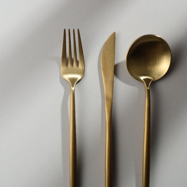 Goldenes minimalistisches Besteck-Set aus Edelstahl, bestehend aus Gabel, Messer und Löffel.