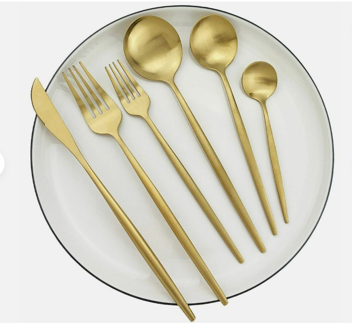 Goldenes Besteckset auf weißem Teller, Edelstahl, modern, Messer, Gabel, Löffel, Teelöffel.