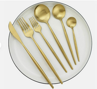 Goldenes Besteckset auf weißem Teller, Edelstahl, modern, Messer, Gabel, Löffel, Teelöffel.