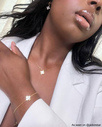 Frau mit goldener Kleeblatt-Schmuckset, Halskette, Armband, Ohrringe, elegantes Design.