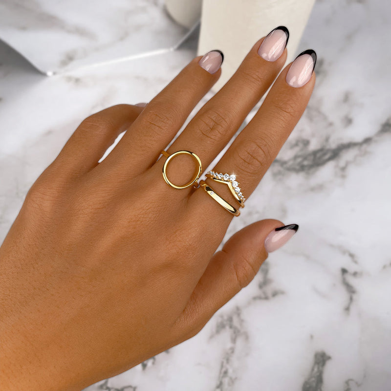 Goldene Ringe auf Hand mit französischer Maniküre, Marmorhintergrund, Schmuck, Modeaccessoire.