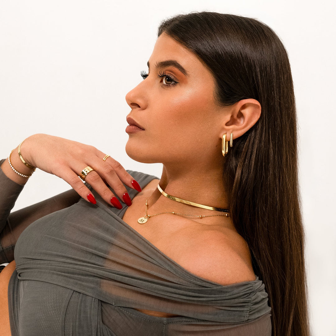 Frau mit goldenen Ohrringen, Halskette und Ringen, elegantes Schmuckset, Modeaccessoires.