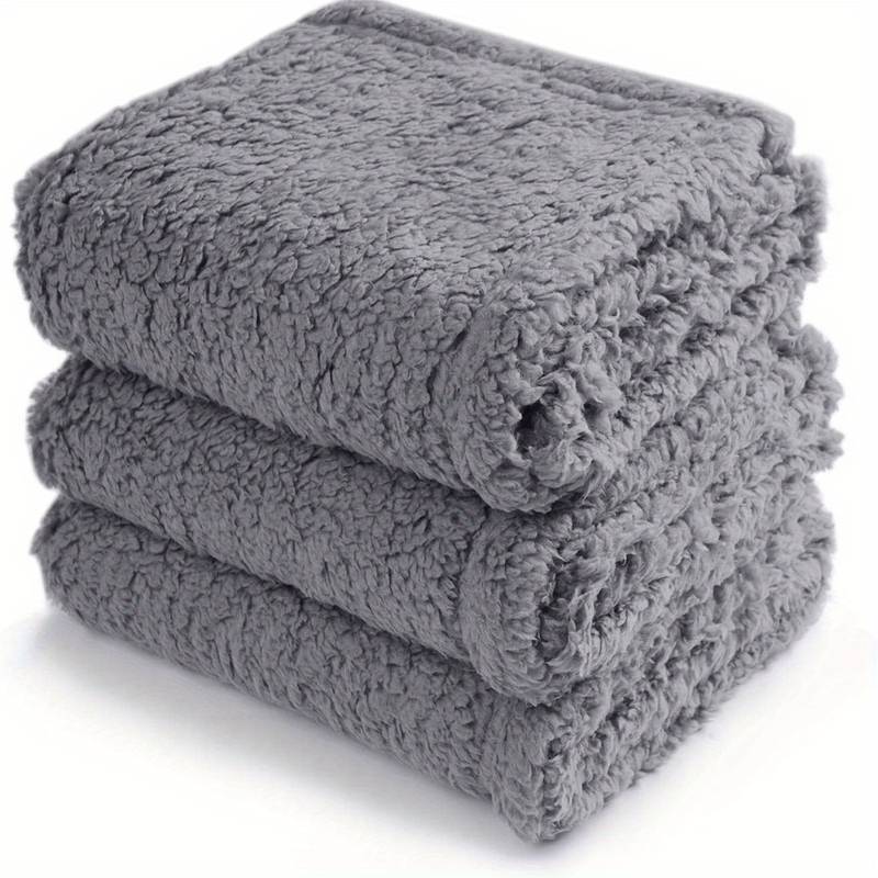 Drei graue, flauschige Handtücher gestapelt, weiches Material, Badezimmerzubehör.