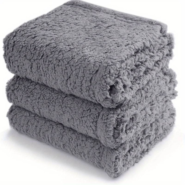 Drei graue, flauschige Handtücher gestapelt, weiches Material, Badezimmerzubehör.