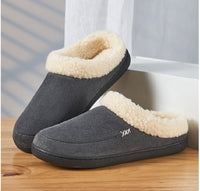 Graue Hausschuhe mit weißem Kunstfellfutter auf Holztisch, gemütlich und warm.