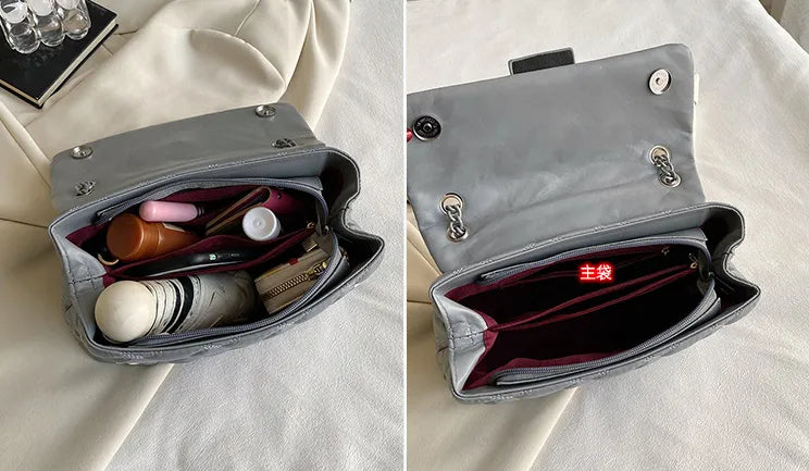 Graue Handtasche aus Leder, geöffnet, mit Kosmetikartikeln und Geldbörse, auf beigem Stoff.