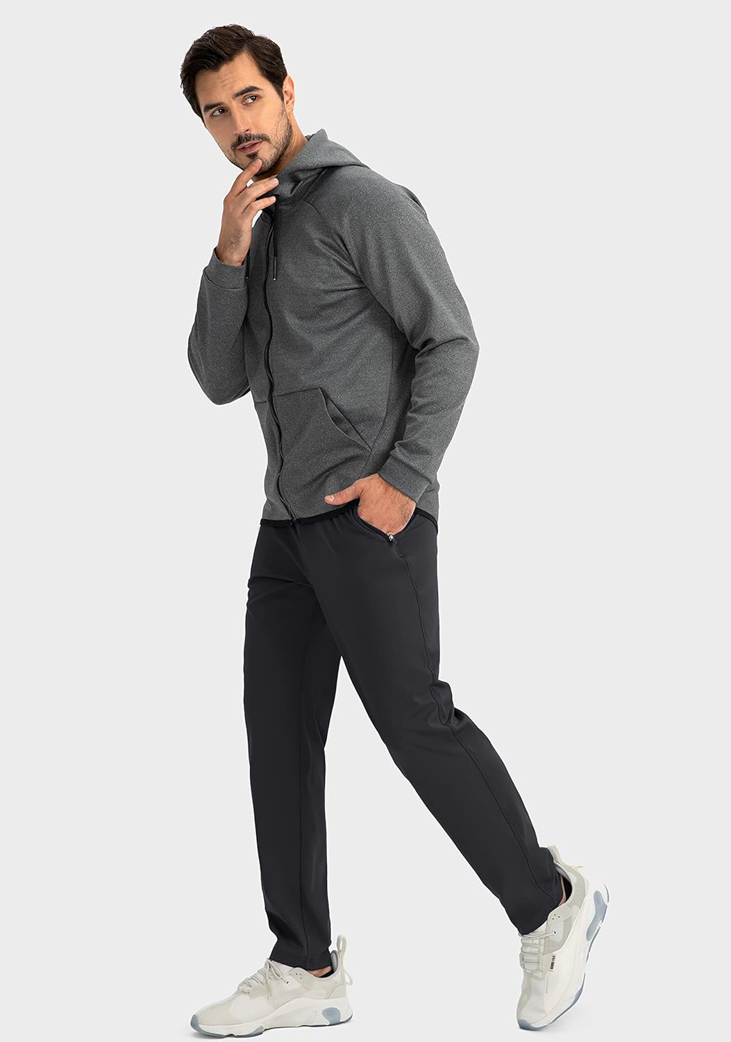 Mann in grauem Hoodie und schwarzer Hose, sportlich, modern, Freizeitkleidung, weiße Sneaker.