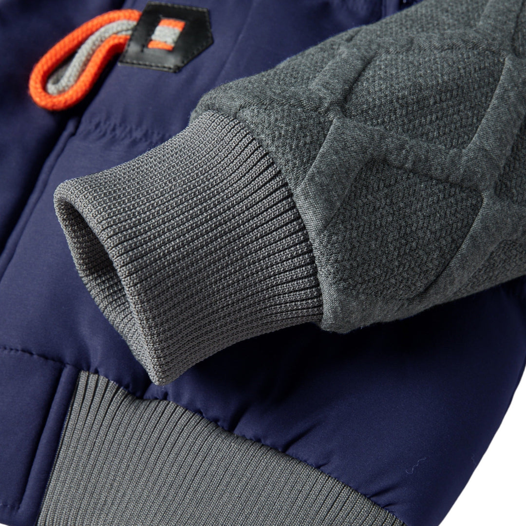 Dunkelblaue Jacke mit grauem Strickbündchen, gesteppter Ärmel, orange Details, Wintermode.