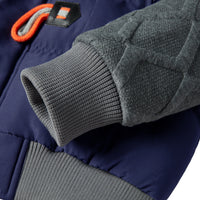 Dunkelblaue Jacke mit grauem Strickbündchen, gesteppter Ärmel, orange Details, Wintermode.