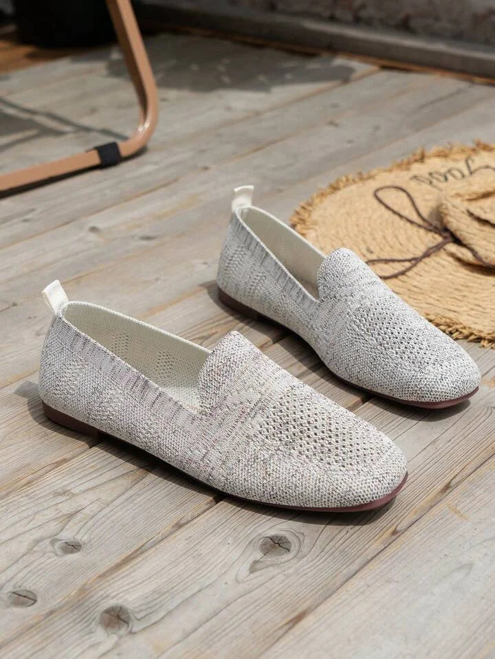 Graue Strick-Slipper für Damen auf Holzboden, bequem und stilvoll, ideal für den Sommer.