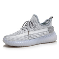 Grauer Sneaker aus Strickmaterial, sportlich, modisch, mit Schnürsenkeln und transparenter Sohle.