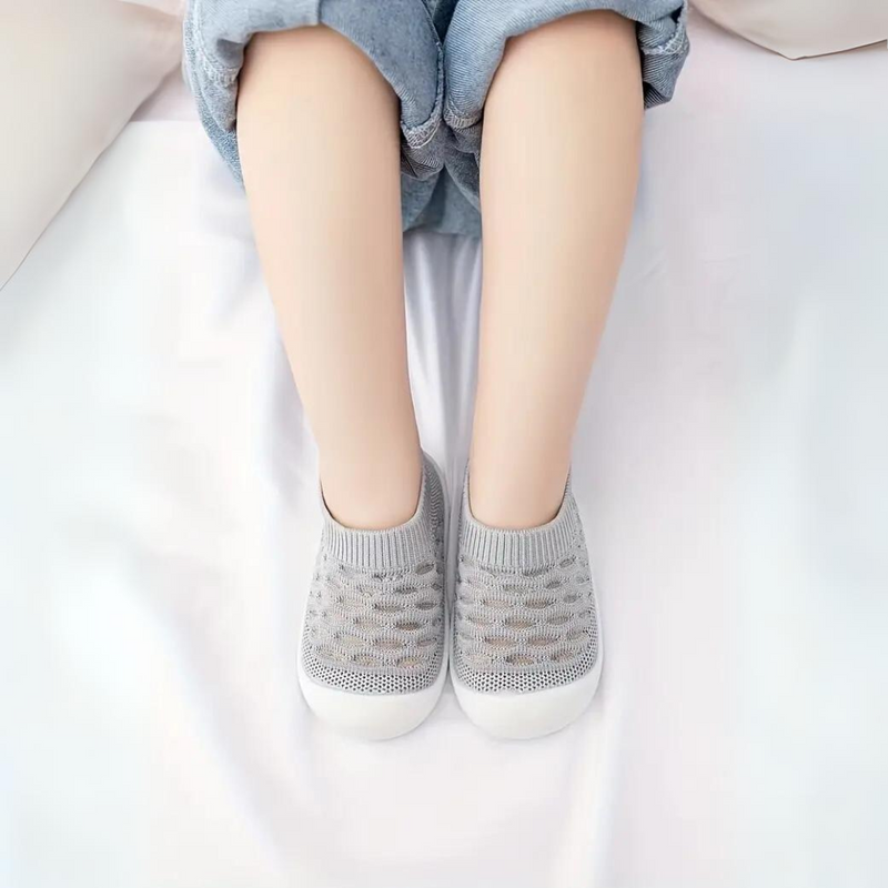 Graue Stricksneaker für Kinder, atmungsaktiv, bequem, auf weißem Hintergrund.