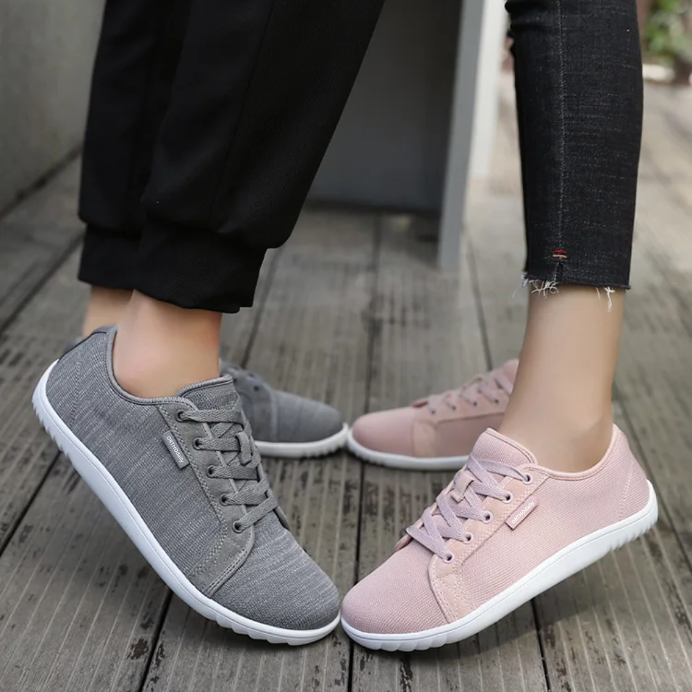 Graue und rosa Sneaker aus Stoff, Damenmode, lässige Schuhe, Holzfußboden.