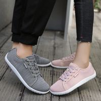 Graue und rosa Sneaker aus Stoff, Damenmode, lässige Schuhe, Holzfußboden.
