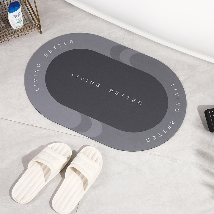 Grauer ovaler Badezimmerteppich mit "Living Better" Schriftzug auf Fliesenboden.