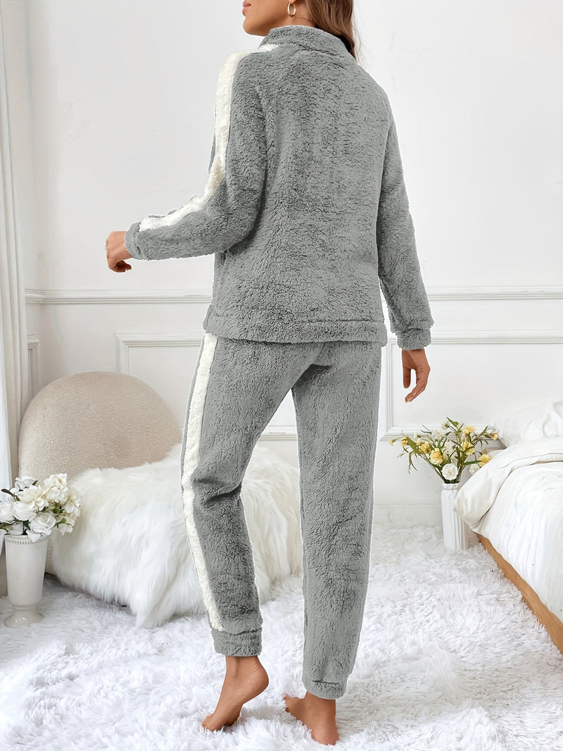Frau in grauem Fleece-Pyjama-Set, gemütlich, modisch, Schlafzimmer, Blumen, Rückansicht.