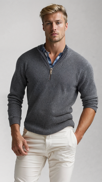 Mann in grauem Strickpullover mit Reißverschluss, blauem Hemd und weißen Hosen vor grauem Hintergrund.