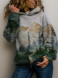 Frau trägt grauen Hoodie mit Berg- und Waldmotiv, Freizeitmode, Baumwolle, Damenbekleidung.