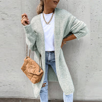 Frau in grauem Strickcardigan, weiße Bluse, Jeans, braune Tasche, modisch, lässig.
