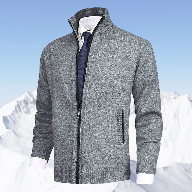 Grauer Herren-Strickjacke mit Reißverschluss, eleganter Stil, vor schneebedeckten Bergen.