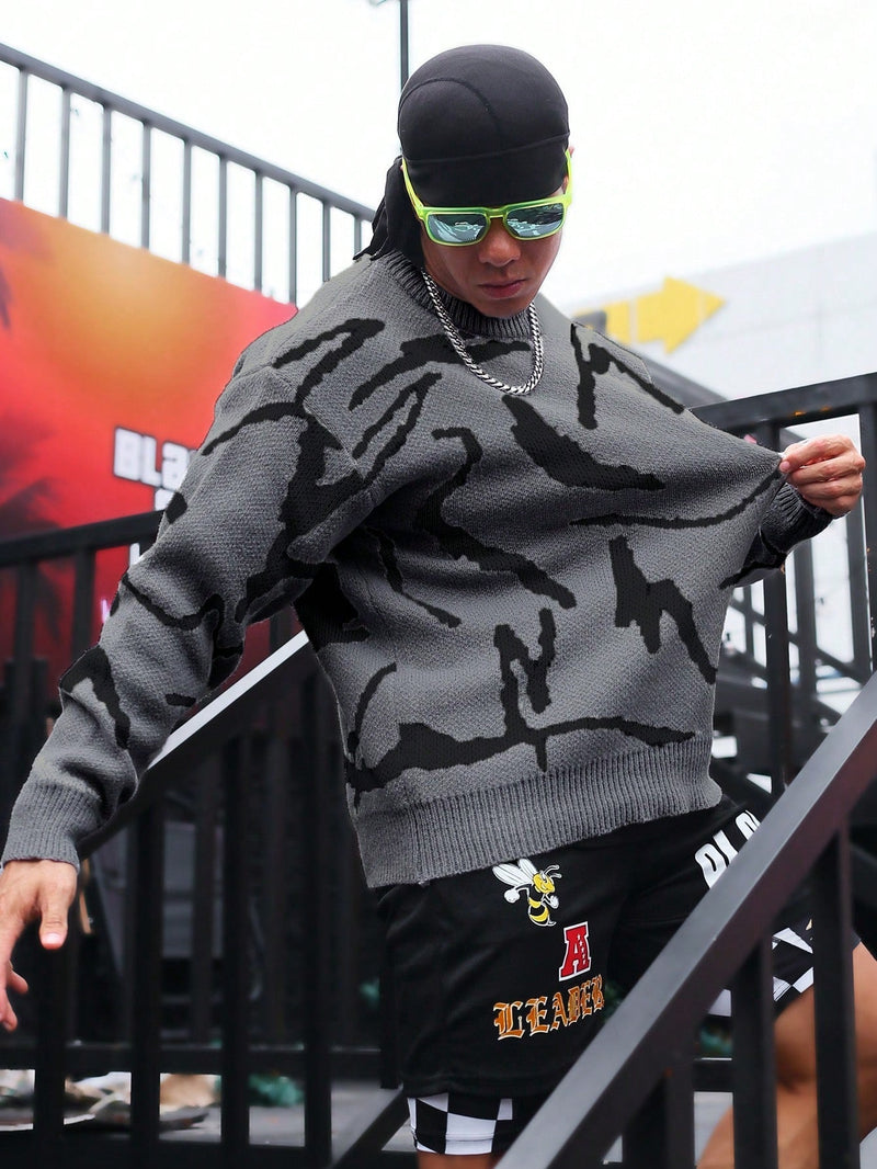 Mann in grauem Camouflage-Pullover, schwarzer Shorts, Sonnenbrille, Kette, auf Treppe.