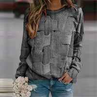 Frau in grauem Strickpullover mit Zopfmuster, hält weiße Rosen, trägt blaue Jeans.