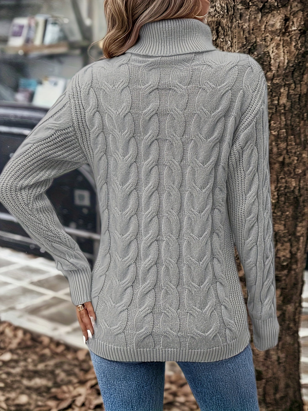 Frau in grauem Strickpullover mit Zopfmuster und Rollkragen, Herbstmode, Rückansicht.