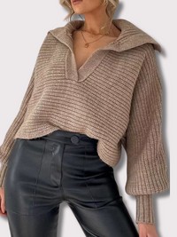 Frau trägt beige Strickpullover mit V-Ausschnitt und schwarze Lederhose, modischer Herbstlook.