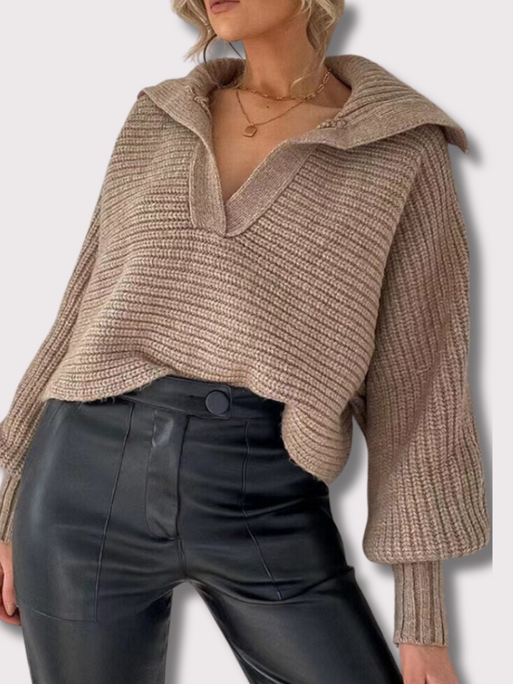 Frau trägt beige Strickpullover mit V-Ausschnitt und schwarze Lederhose, modischer Herbstlook.