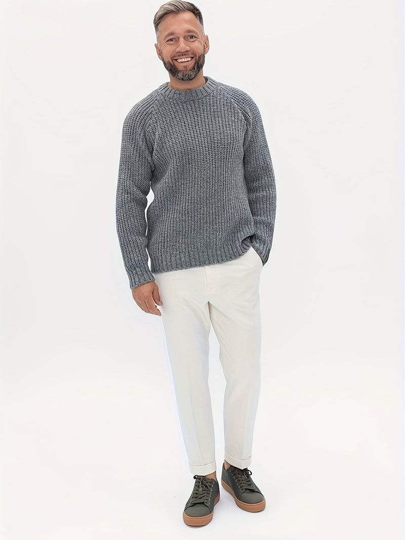 Mann in grauem Strickpullover und weißen Hosen, lächelnd, modisch, Freizeitkleidung.