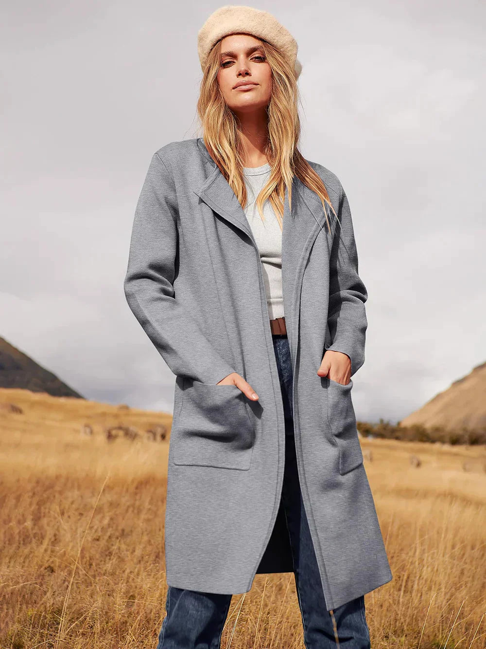 Frau in grauem Mantel und Mütze in Landschaft, Herbstmode, Damenbekleidung, Outdoor-Stil.