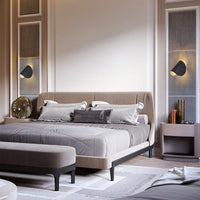 Modernes Schlafzimmer mit grauem Polsterbett, Nachttisch und stilvollen Wandlampen.