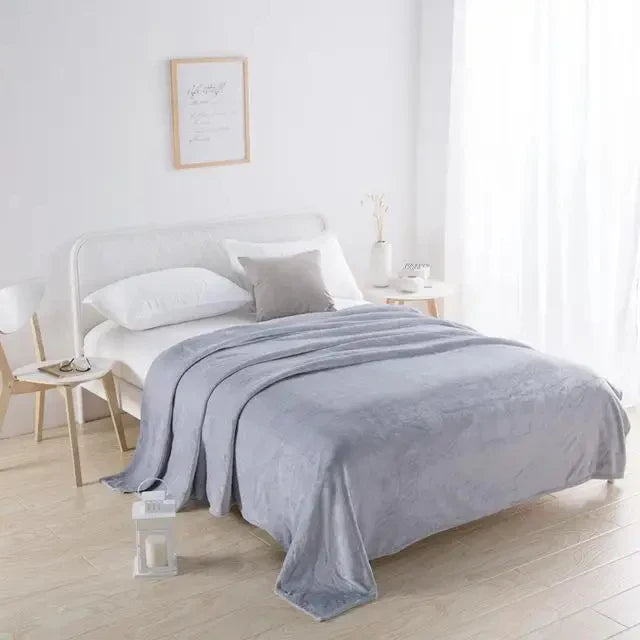 Graues Bett mit Decke, Kissen und Nachttisch in modernem Schlafzimmer, skandinavisches Design.