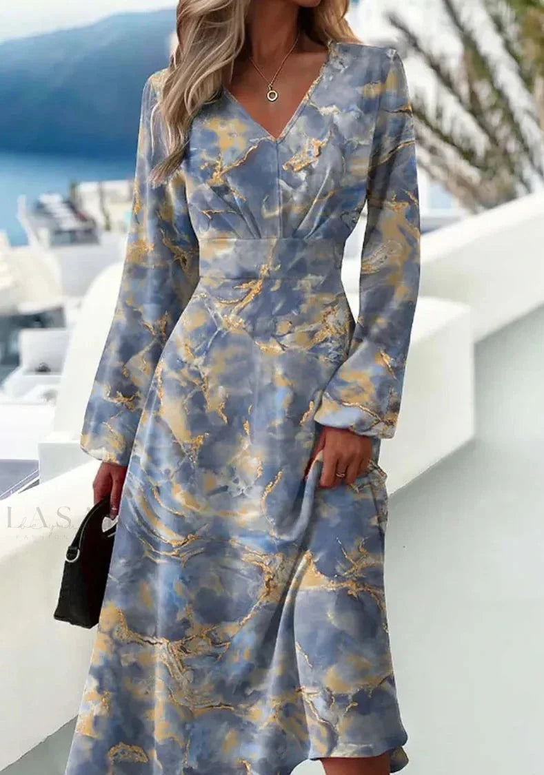 Frau in blau-grauem, marmoriertem Maxikleid mit langen Ärmeln, elegantes Design, draußen.