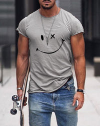 Mann in grauem T-Shirt mit Smiley-Design, Jeans, Skateboard, urbaner Hintergrund.