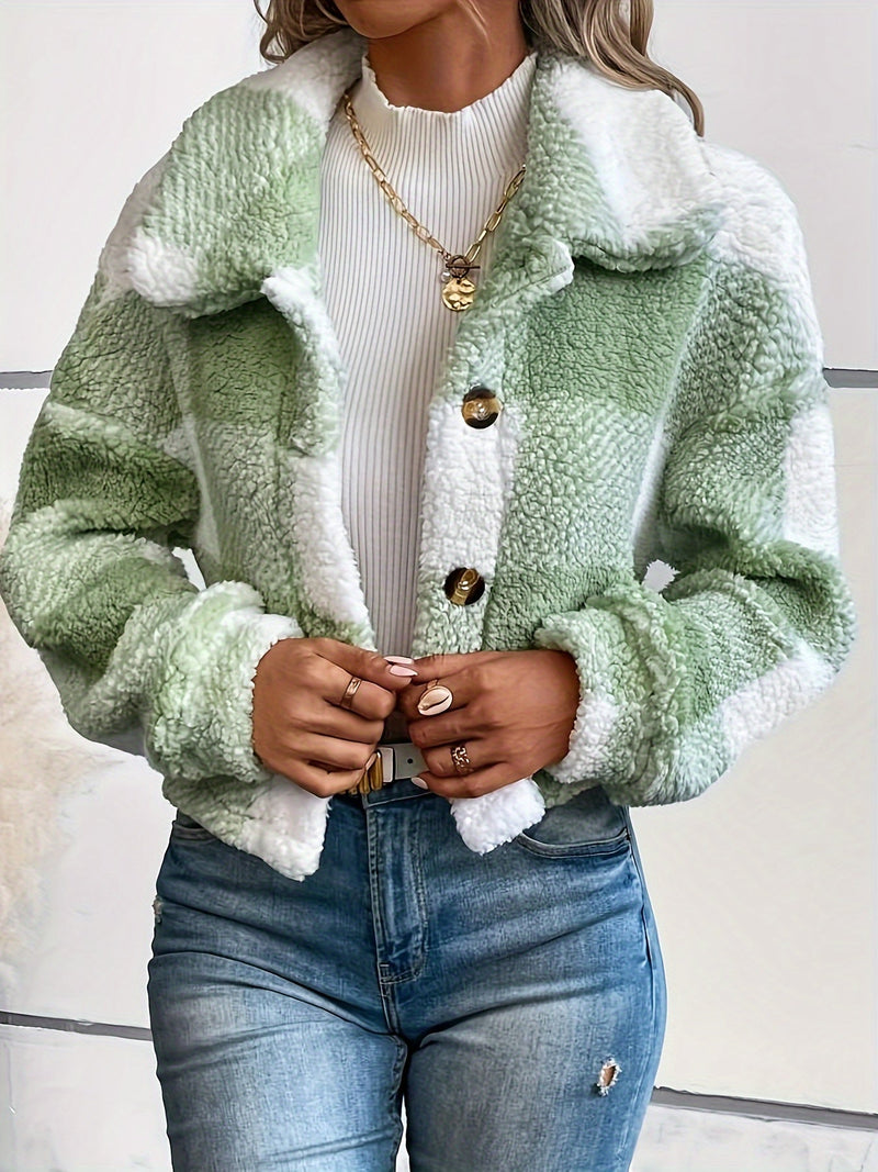 Frau in grün-weiß karierter Teddyjacke, Jeans, weißem Pullover, goldene Kette.