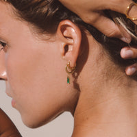 Frau mit goldenen Ohrringen und grünem Anhänger, Sommermode, Schmucktrends 2023.