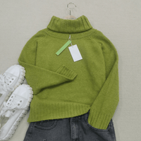 Grüner Rollkragenpullover aus Wolle, Damenmode, Herbst, neben weißen Sneakers und Jeans.