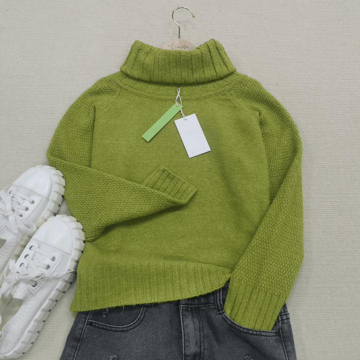 Grüner Rollkragenpullover aus Wolle, Damenmode, Herbst, neben weißen Sneakers und Jeans.
