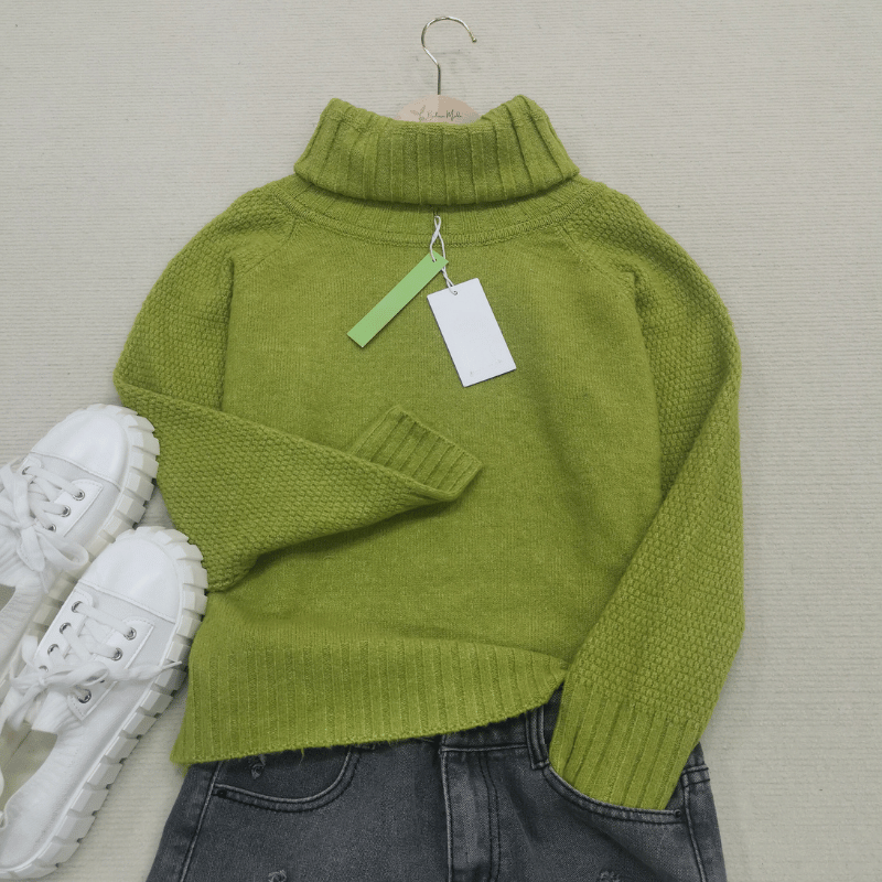 Grüner Rollkragenpullover aus Wolle, Damenmode, Herbst, neben weißen Sneakers und Jeans.