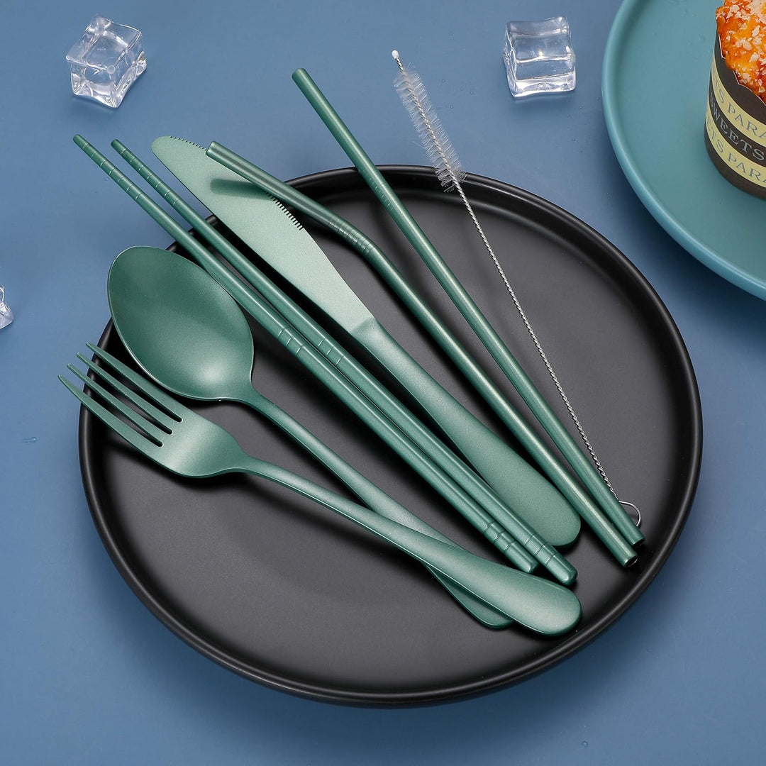 Grünes Besteckset aus Edelstahl auf schwarzem Teller, inkl. Strohhalm und Reinigungsbürste.