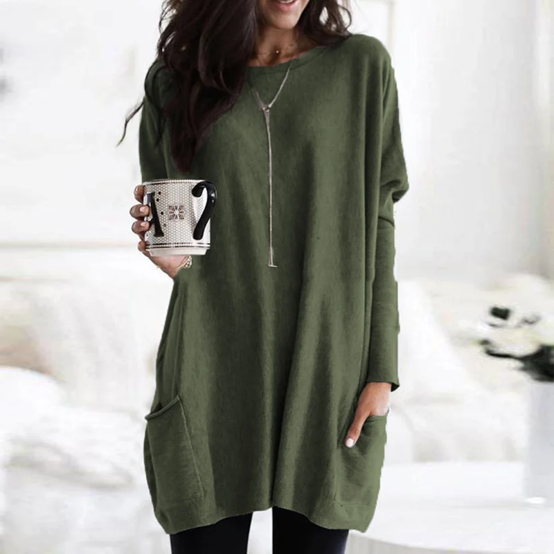 Frau in grünem Oversize-Pullover mit Kaffeetasse, gemütliche Herbstmode, Wohnzimmer.