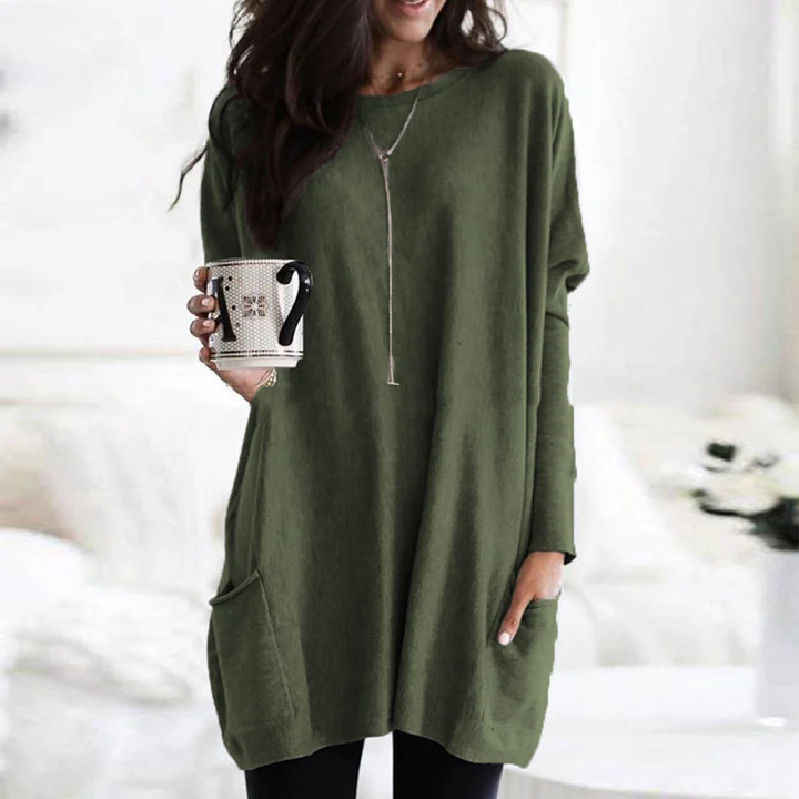 Frau in grünem Oversize-Pullover mit Kaffeetasse, gemütliche Herbstmode, Wohnzimmer.