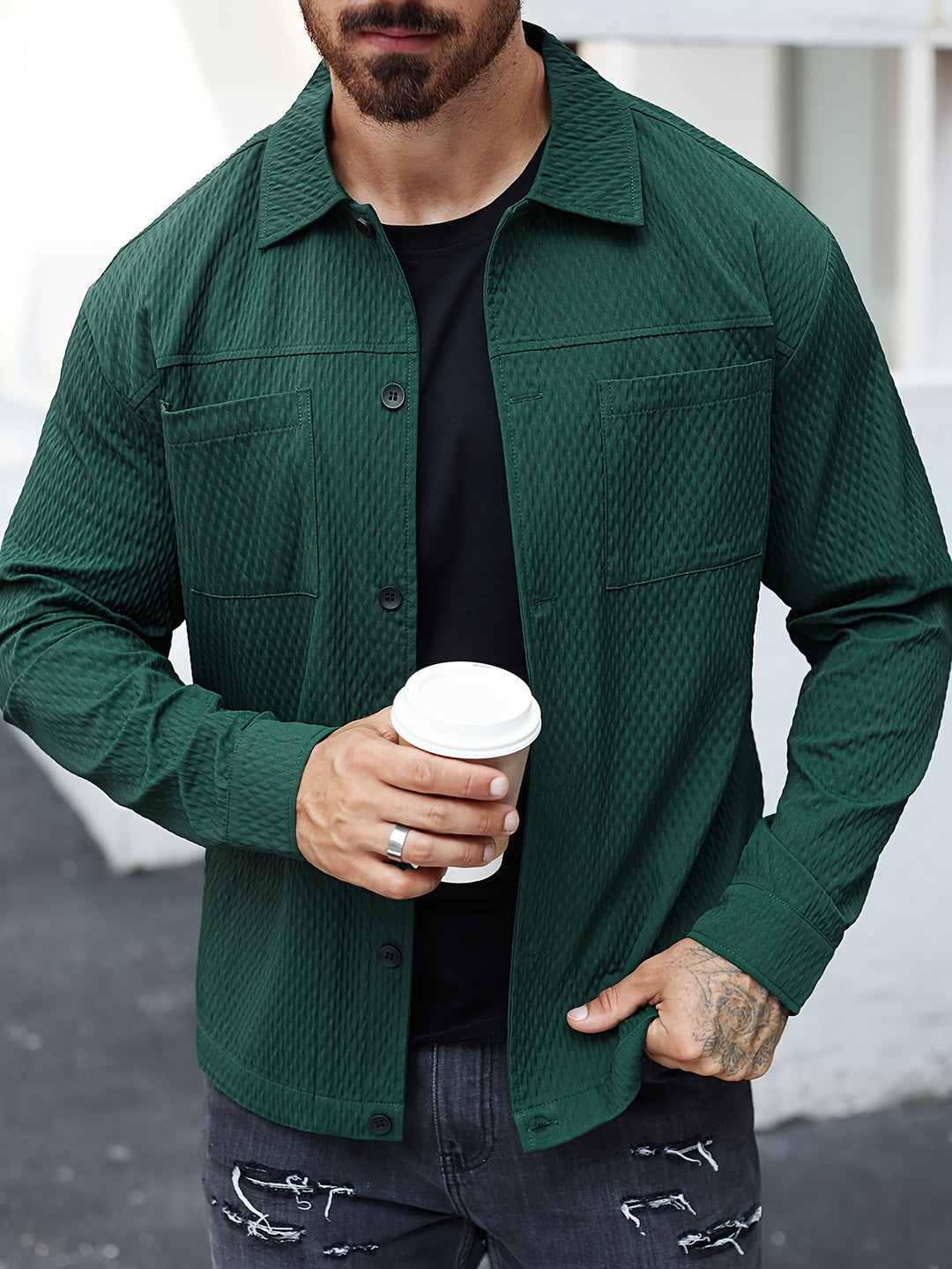 Mann in grüner Jacke mit Kaffeebecher, schwarze Jeans, urbaner Stil, Freizeitmode.