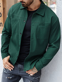 Mann in grüner Steppjacke, schwarzem T-Shirt und grauer Jeans mit Rissen, lässiger Streetwear-Look.