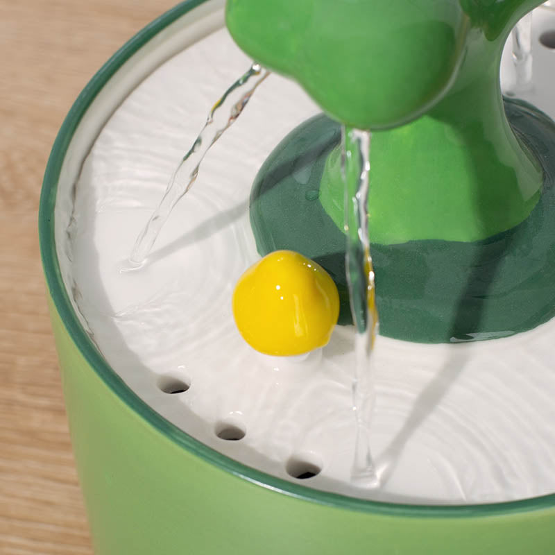 Grüner Keramik-Katzentrinkbrunnen mit gelber Kugel, Wasserstrahlen, modernes Design.