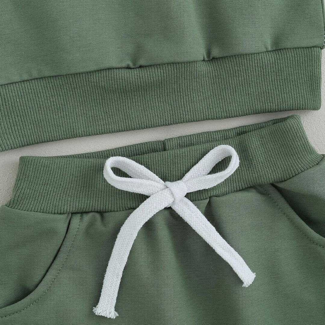 Grüner Baby-Sweatanzug aus Baumwolle mit weißer Kordel, bequem und modisch.