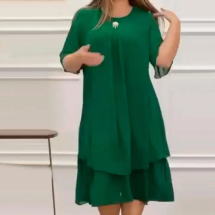 Frau in grünem Kleid, knielang, mit kurzen Ärmeln, elegantes Design, Innenraum.