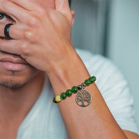 Mann mit grünem Armband und Lebensbaum-Anhänger, modisches Accessoire, Nahaufnahme.