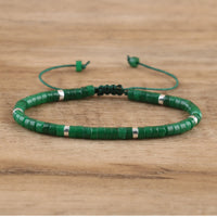 Grünes Perlenarmband aus Jade mit verstellbarem Verschluss auf Holzoberfläche.